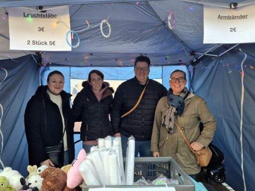 Vier Personen stehen in einem Zelt, umgeben von Spielzeug und Dekoration.