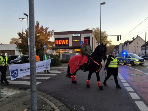 Demonstration mit einem Reiter auf einem Pferd, Polizeiautos und Banner im Hintergrund.