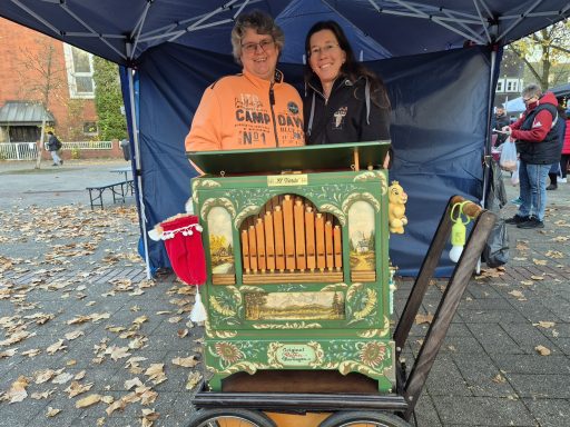 Zwei Personen stehen vor einem musikalischen Handorgel auf einem belebten Platz.