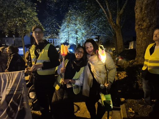 Zwei Personen lächeln, halten leuchtende Gegenstände und tragen reflektierende Westen.