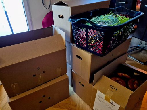 Stapel von Kartons und einem Korb mit bunten Objekten.