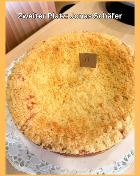 Ein runder Kuchen mit goldbrauner Kruste und einem kleinen Schildchen oben.