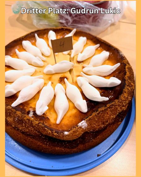 Käsekuchen mit weißen, dekorativen Figuren in kreisförmiger Anordnung.